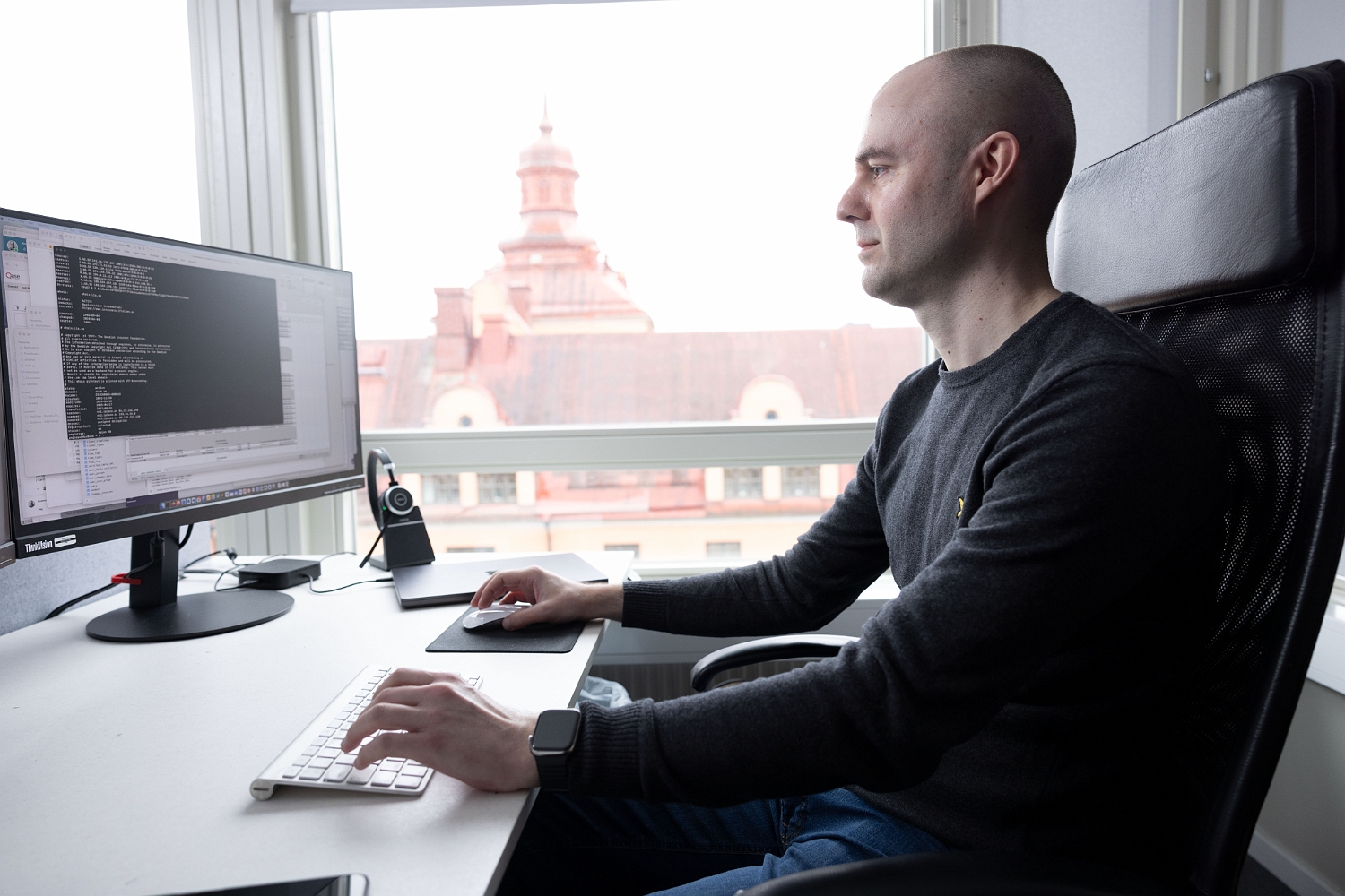 En person arbetar vid två datorskärmar i ett kontor. Security Awareness-plattformen testar och utbildar användare för att höja säkerhetsmedvetandet och minska risken för cyberangrepp.